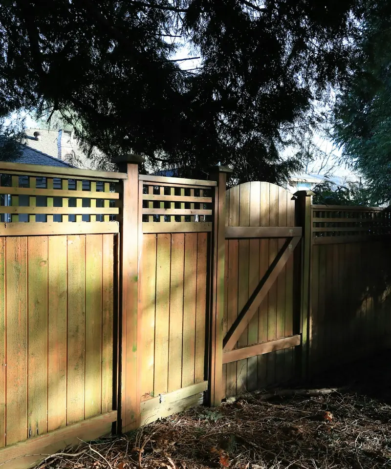 New stained wood privacy fence with a lattice top and a matching walk gate set on heavy posts