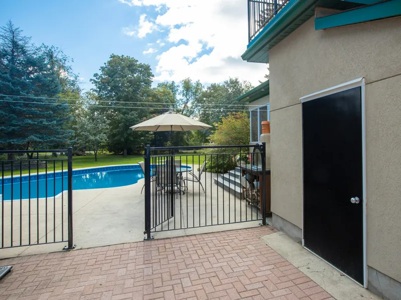 Black aluminum pool fence with a self-closing gate around a backyard swimming pool and patio
